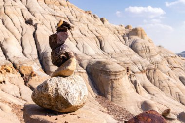 Stack of bright orange and sandy balancing rocks in the scenic badlands, eroded formations in canyon. Hoodoos trail, Drumheller, Alberta, Canada. clipart