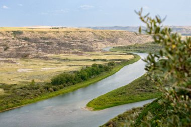 Çorak topraklar boyunca uzanan vadideki tepeden nehre kadar uzanan harika bir yaz manzarası. Kızıl Geyik Nehri, Orkney Gözcüsü, Alberta, Kanada.