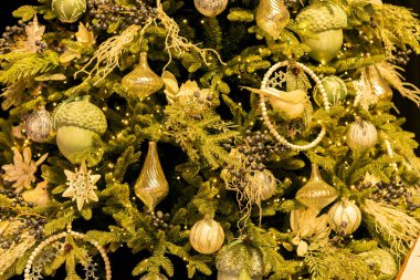 Bej meşe palamudu, kuş, top, çimen, buz saçakları, kar taneleri ve ışıklarla süslenmiş yaratıcı Noel ağacı..