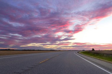 Ovalarda muhteşem mor ve pembe gün batımı... kırsal kesimde otoyolda bulutlu bir gökyüzü....