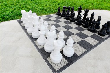 Dev açık hava satranç takımı, açık hava aktiviteleri için otel bahçesindeki panoda beyaz ve siyah biblolar..