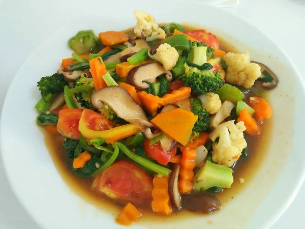 Stir fried vegetables in a white plate on a white background.