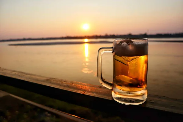 Mug of beer with ice on the beach in the evening.