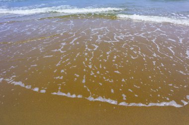 Kumlu sahilde denizin yumuşak dalgalarına yakın çekim. 
