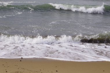 Akdeniz 'in dalgaları kumlu sahilde kırılıyor.