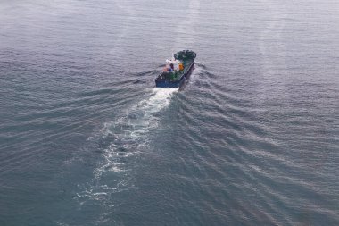 Mavi denizde giden bir kargo gemisinin hava görüntüsü. Yukarıdan görüntüle.