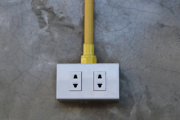 Electrical plug and socket on a concrete wall with copy space.