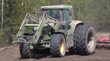 Tarım, bahar işleri. Disk harrow seviyesine sahip traktör tarladaki toprağı gevşetiyor.