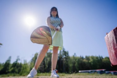 Olgun kadın golf sahasında şoförle golf oynamaya hazırlanıyor, yakın çekim, düşük bölüm, golf topuna odaklan.