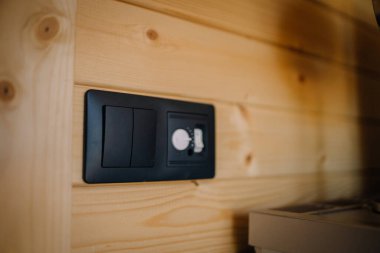 Ahşap bir duvara karşı çift lamba anahtarı için siyah bir cüzdan soketinin görüntüsünü kapat.