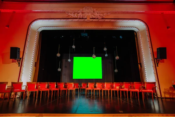 Red chairs are arranged on the Theater stage with green screen