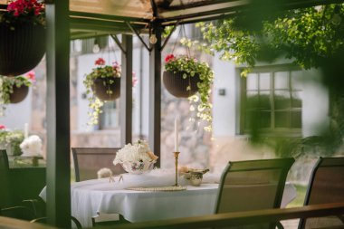 Terasa beyaz bir masa konur ve yaz aylarında çiçeklerle süslenir. Çiçekler günbatımında tencerelere asılır.