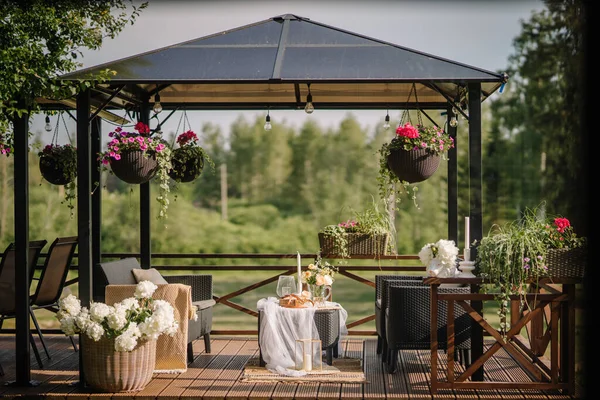 一个白色的桌子放在阳台上 夏天装饰着花朵 日落时挂在盆子里 — 图库照片