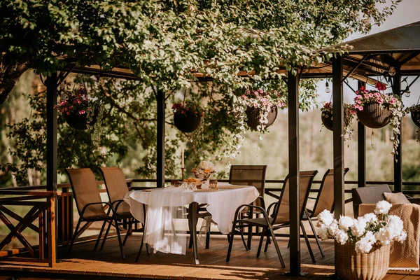 一个白色的桌子放在阳台上 夏天装饰着花朵 日落时挂在盆子里 — 图库照片