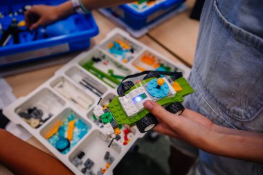 Küçük çocuk ellerini yeni bir şekle sokarken, bloklardan plastik oyuncak arabaya odaklan..