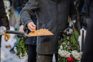 Cenaze ritüeli. Kum kürekten elle alınıp ölüye veda edildiğinde savaş kurbanları gömülür.