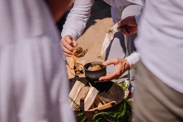 Ritual, lighting a fire close up in sunny weather in summer. The fireplace is decorated with greenery.