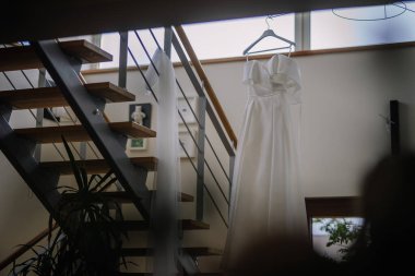 Narin bir gelinlik güzel bir merdiven korkuluğunda asılı.