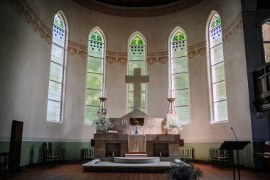 Kilisenin içi güzel vitraylı pencerelerle süslü ahşap banklar ve muhteşem bir sunakla.