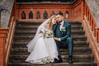 Şehvetli romantik yeni evli çift eski barok merdivenlerde oturuyor.