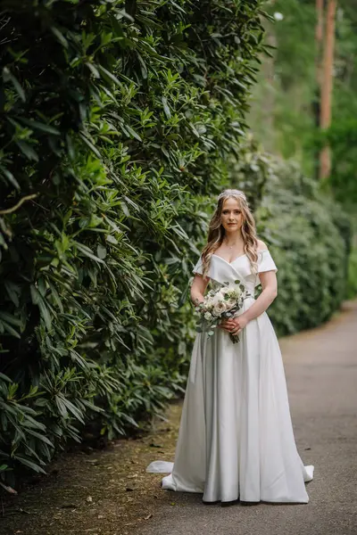 Красивая Невеста Длинным Платьем Стоит Природе Зелени Большим Букетом Свадебный — стоковое фото