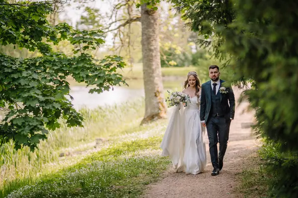 Wedding and marriage concept. Bride and groom walking in fairytale park after wedding ceremony