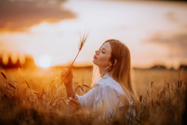 Bir kadın elinde mısır sapıyla gün batımına hayran olur.