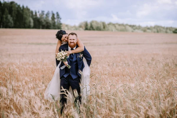 The couple runs and laughs, with the bride joyfully jumping onto the groom's back, showcasing their deep and affectionate love in the open field