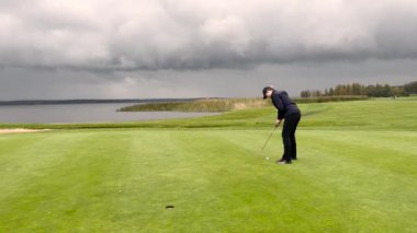 Golf sahasında rüzgarlı yağmurlu bir günde golf sopasıyla golf oynayan