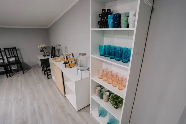 Cozy interior with stylish furniture and modern design. Empty stylish glasses on shelf unit near wall