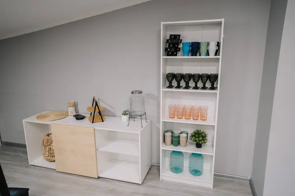 Cozy interior with stylish furniture and modern design. Empty stylish glasses on shelf unit near wall