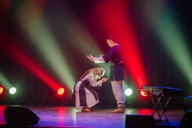 Sahnede sahne ışıkları altında dans eden profesyonel çift sigara içiyor. Sahne ışıkları altında güzel bir genç kadın ve erkek. Duygusal düet yapan koreografik sanat.