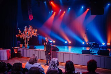 Akşamın ev sahibi, sahnede farklı ışıklarla.