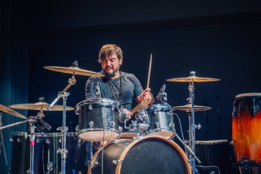 Davulcu arka planda toz ve dumanla davul çalıyor