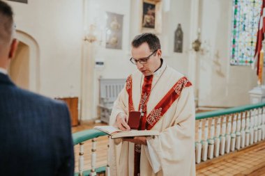 Kilisedeki düğün töreni için papazın önünde duran çift. Gelin ve damat düğün törenlerinde rahibin huzurunda dururlar.