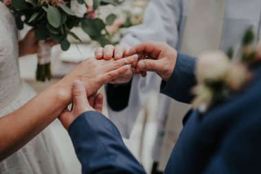 close-up, the bride and groom wear rings to each other, against the background of the sea, sand and blue sky. summer, day. High quality photo