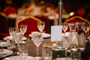 Şarap bardakları ön planda. Düğün Ziyafeti ya da gala yemeği. Misafirler için sandalye ve masa, çatal bıçak takımı ve tabak ile servis.