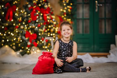 Siyah elbiseli, Noel atmosferinde yıldızlar olan küçük bir kız. Kız Noel için mutlu. Noel süslemeleri.