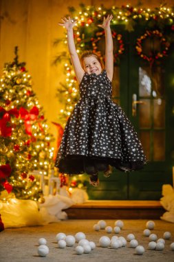 Siyah elbiseli, Noel atmosferinde yıldızlar olan küçük bir kız. Kız Noel için mutlu. Noel süslemeleri.