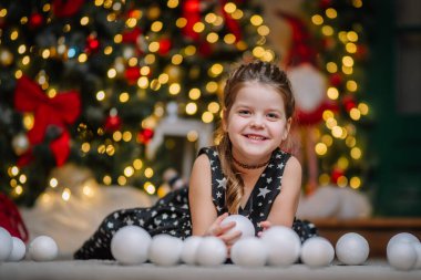 Siyah elbiseli, Noel atmosferinde yıldızlar olan küçük bir kız. Kız Noel için mutlu. Noel süslemeleri.