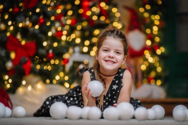 Siyah elbiseli, Noel atmosferinde yıldızlar olan küçük bir kız. Kız Noel için mutlu. Noel süslemeleri.