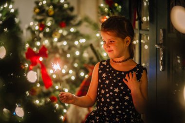 Siyah elbiseli, Noel atmosferinde yıldızlar olan küçük bir kız. Kız Noel için mutlu. Noel süslemeleri.