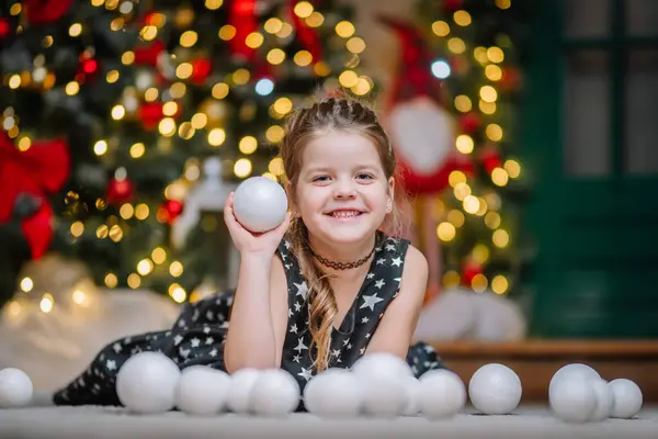 Siyah elbiseli, Noel atmosferinde yıldızlar olan küçük bir kız. Kız Noel için mutlu. Noel süslemeleri.