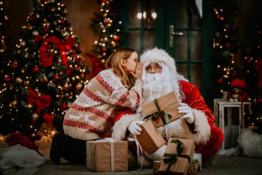 Küçük kız Noel Baba 'nın kulağına fısıldıyor. Bir sır söylemek. Kazanmak istediğin hediyeyi ortaya çıkarmak. Yıl boyunca nasıl davrandığından bahsediyordu..