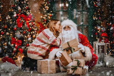 Küçük kız Noel Baba 'nın kulağına fısıldıyor. Bir sır söylemek. Kazanmak istediğin hediyeyi ortaya çıkarmak. Yıl boyunca nasıl davrandığından bahsediyordu..