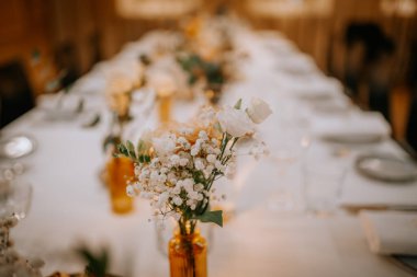 Restoranda güller, yeşillikler ve orkide çiçekleri olan güzel düğün süsleri.