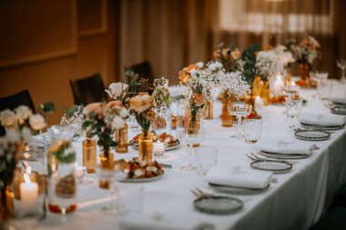 Restoranda güller, yeşillikler ve orkide çiçekleri olan güzel düğün süsleri.