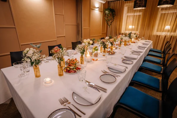 a long table served with dishes and flowers.