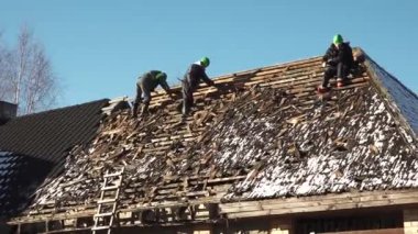 Cesis, Letonya - 30 Kasım 2023 - eski bir çatıda çalışan adamların fotoğrafları. Eski fayansların kaldırılması ve çatı inşaatının yeni fayanslar için hazırlanması.