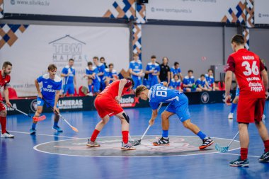 Valmiera, Letonya - 15 Aralık 2023 - iki erkek zemin topu takımı kapalı alanda birbirlerine karşı oynuyorlar. Oyun anları ve taraftarlar. Uygunsuz spor.